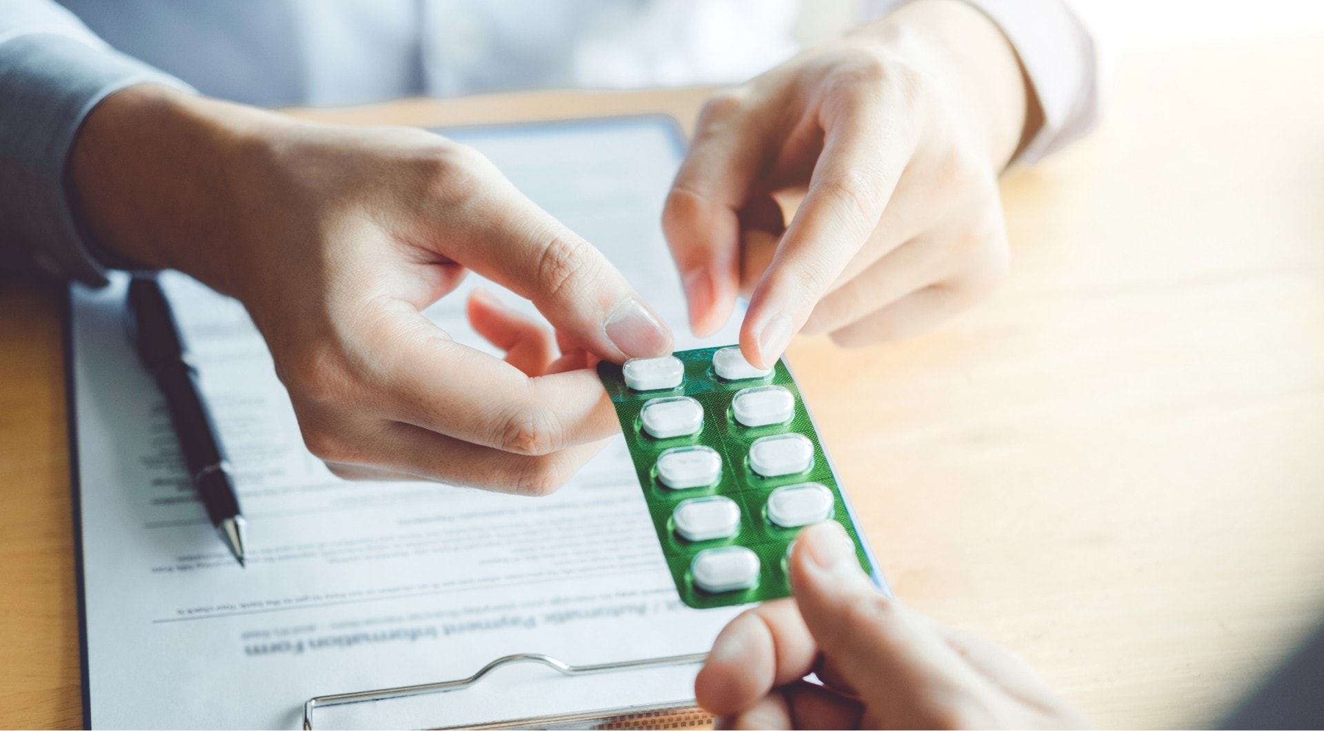 A doctor handing a set of pills to a patient at a desk